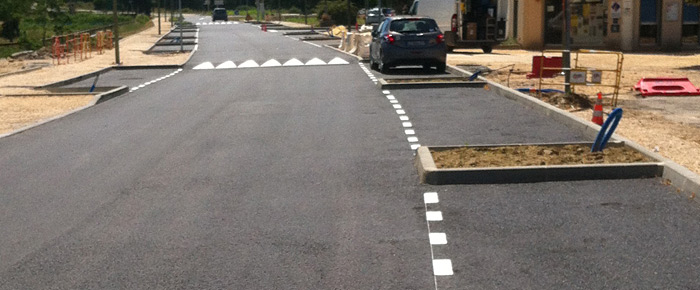 Stationnement, ralentisseur et route dans un village de Haute-Garonne